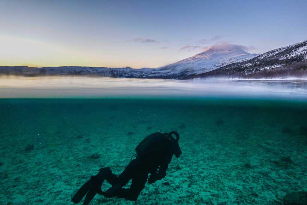 Ein dykkar under vatn. Overvatn eit snødekt landskap.