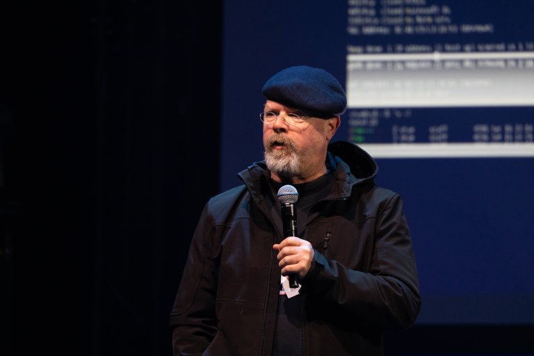 Portrett. Jamie Hyneman snakker i mikrofon på sen scene.