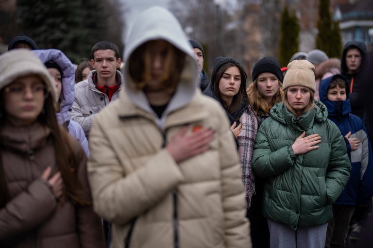 Sørgende ungdommer holder hånden til hjertet mens den Ukrainske nasjonalsangen spilles i en begravelse.