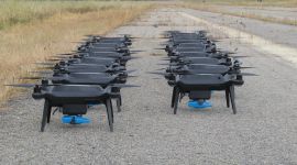 Mange droner oppstilt på bakken. Foto