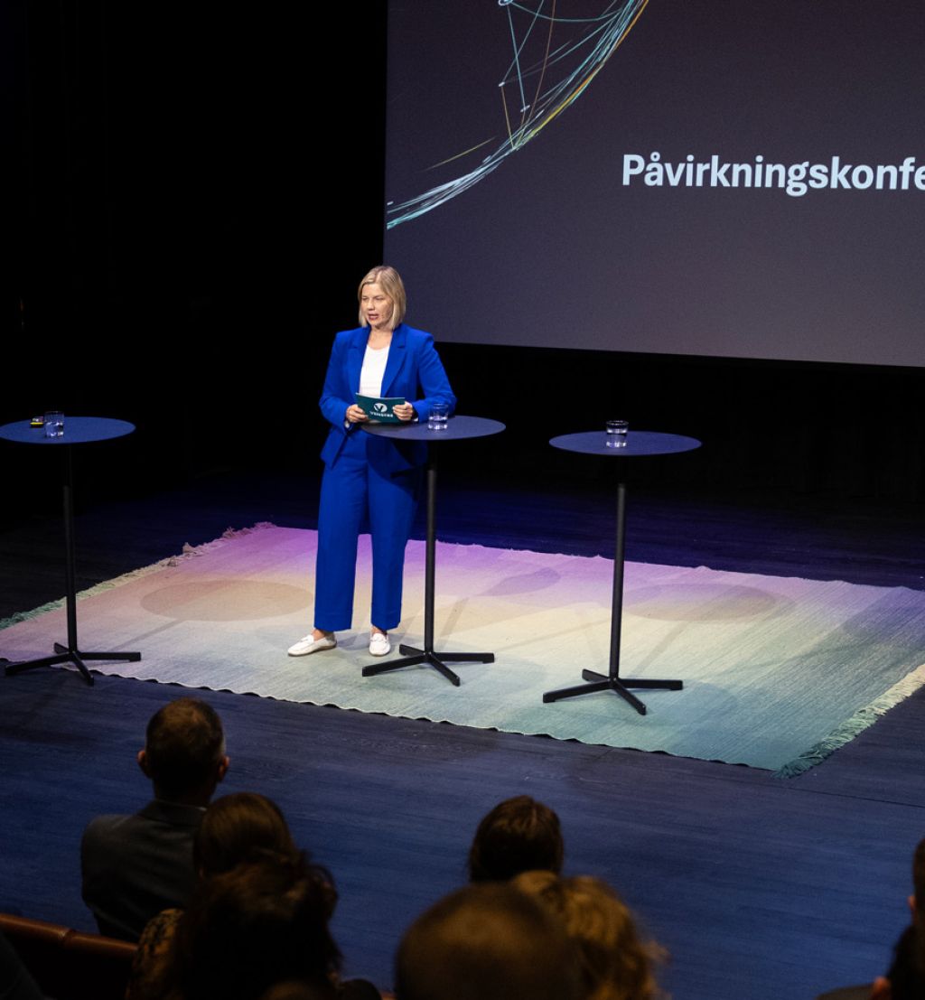 Guri Melby på scenen i blå drakt under Påvirkningskonferansen 2025.
