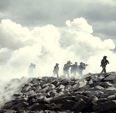 Seks spesialsoldater kommer ut av en røyksky.