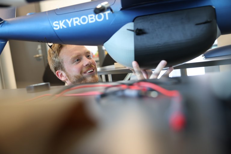 Student fester et 3D printet panel på undersiden av en fixed wing drone.