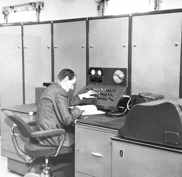 Harald Keilhau sitter ved FFIs første digitale datamaskin med 2000 vakuumrør og 20 kW varmetap. Ferranti Rapid Electronic Defence Research Institute Computer (FREDRIC) representerte et gjennombrudd i hvordan forskerne løste kompliserte matematiske problemer. 