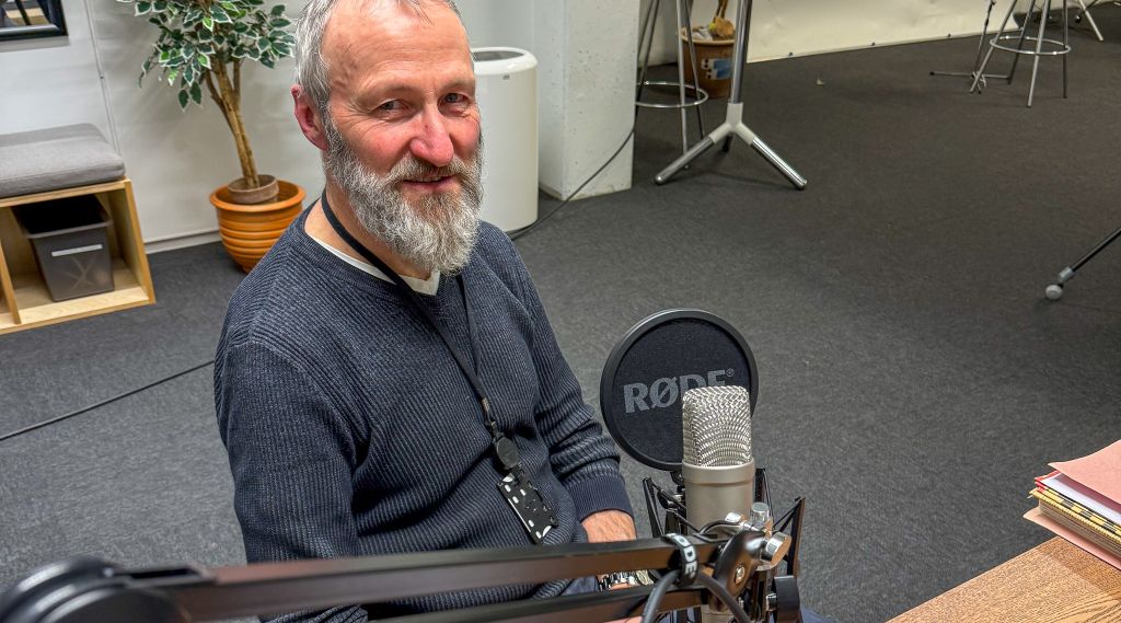 Forsker bak mikrofonen i podkaststudio.