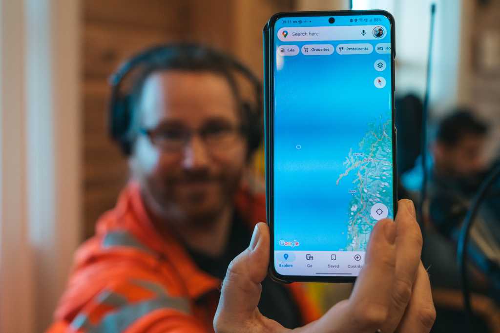 Mann holder opp en mobiltelefon med kart.