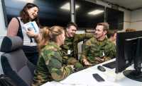 A scientist and three students in uniform in front of a computer