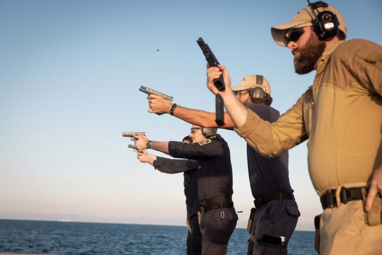  Four men practice pistol shooting on board HMS Roald Amundsen.