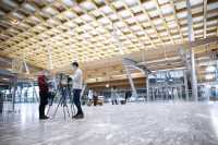 Two researchers standing up close to testing equipment in a large airport hall.