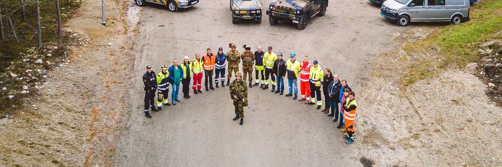 A lot of people in different uniforms are standing in a semicircle around a soldier.