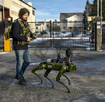 Robothund går ute sammen med mann med fjernkontroll. Foto