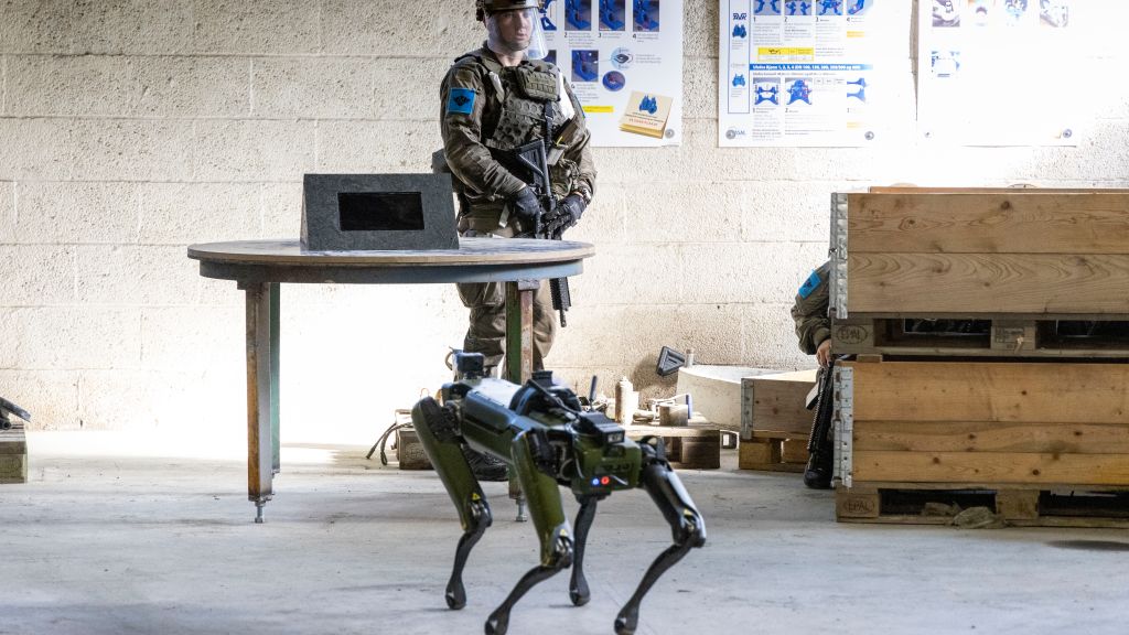Robothund går mot bevepnet soldat. Foto