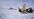 en fregatt ligger i isen. i forgrunnen ser man tre forskere i boblejakkre som ordner med en parabolantenne
