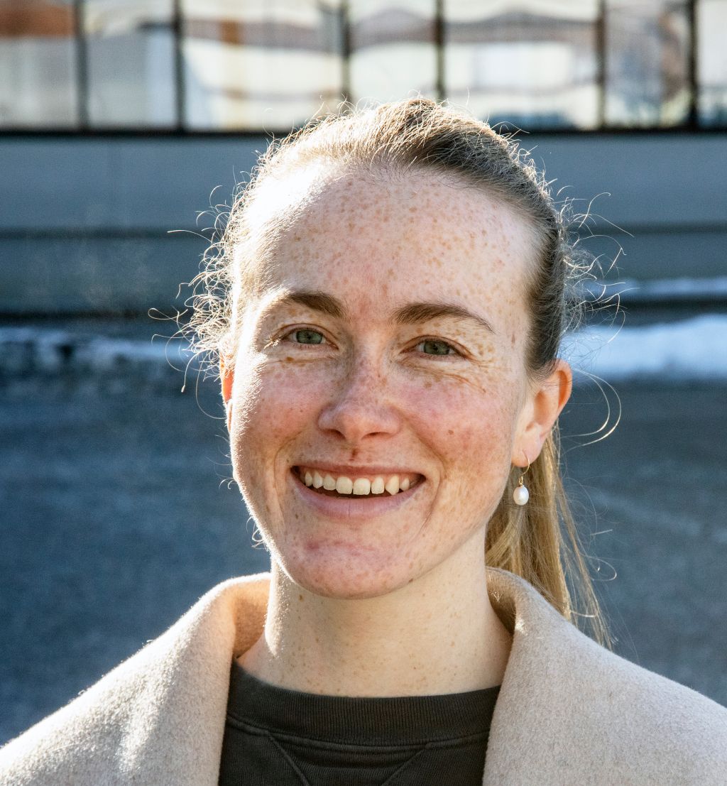 Smilende kvinne står utendørs og ser mot kamera