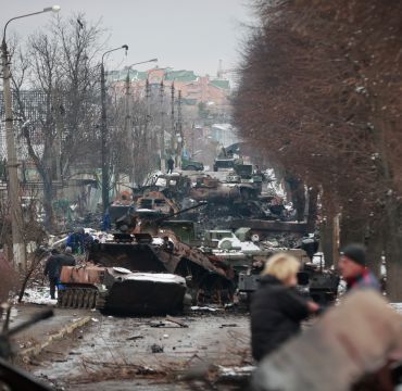 People look at the gutted remains of Russian military vehicles on a road in the town of Bucha, close to the capital Kyiv, Ukraine, Tuesday, March 1, 2022