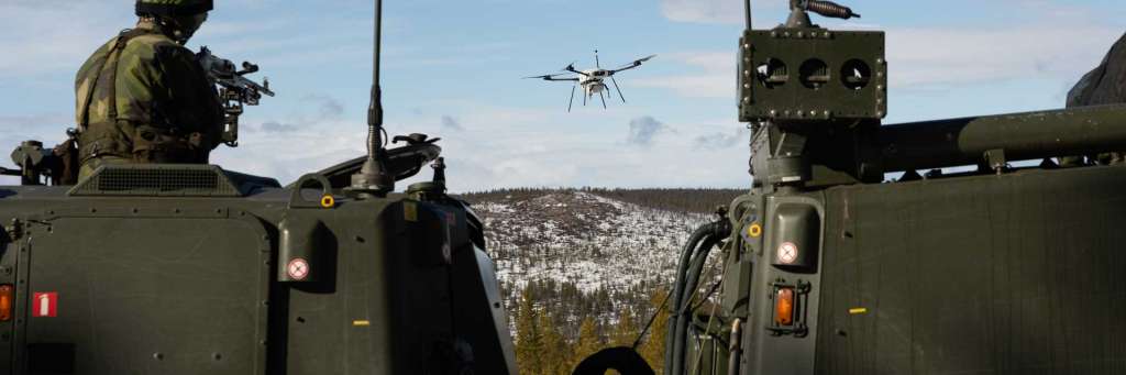 En soldat på et kjøretøy sikter på en drone med et våpen.