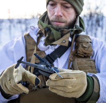 Soldat i vinteruniform som holder en drone, en Black Hornet 3.