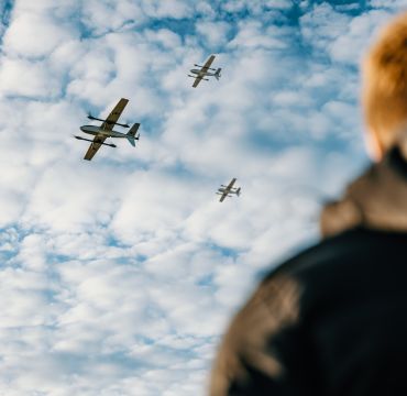 En person ser opp på tre droner som flyr forbi.