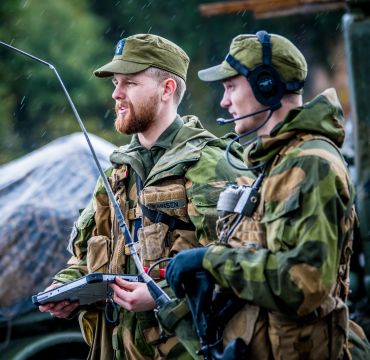 To militærkledde menn med samband på øret og nettbrett i hånda