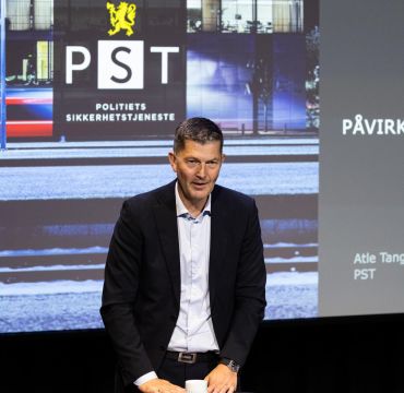 Atle Tangen i PST foran en presentasjon som viser logoen til Politiets sikkerhetstjeneste.