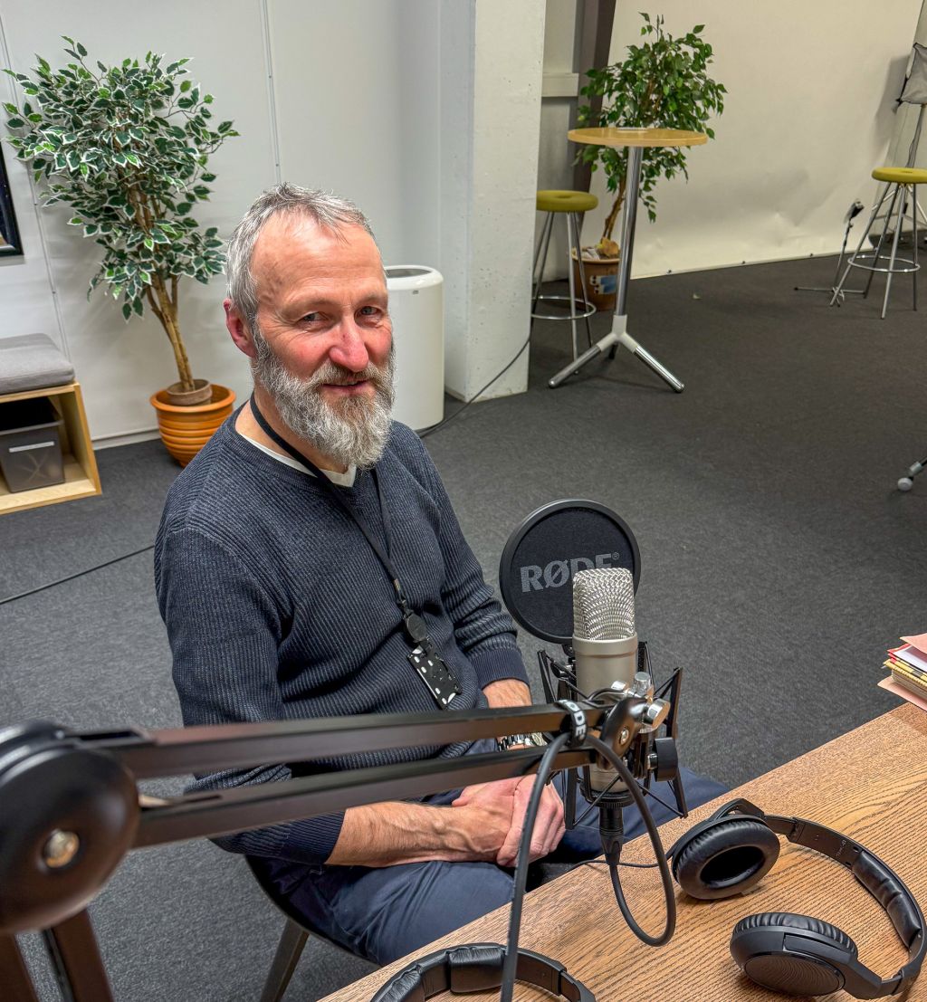 Forsker bak mikrofonen i podkaststudio.