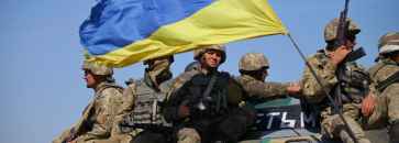 Soldater sitter på tanks med ukrainsk flagg. Foto