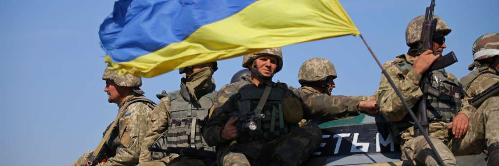 Soldater sitter på tanks med ukrainsk flagg. Foto