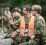 Soldater i kamuflasjeuniform på øvelse. En elev og en instruktør står og ser på noe og diskuterer.