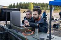 To menn ser på laptop mens de står utendørs på et militært øvingsfelt