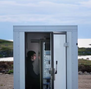 Ung mann sitter i en kontainer som er plassert ved like ved havet