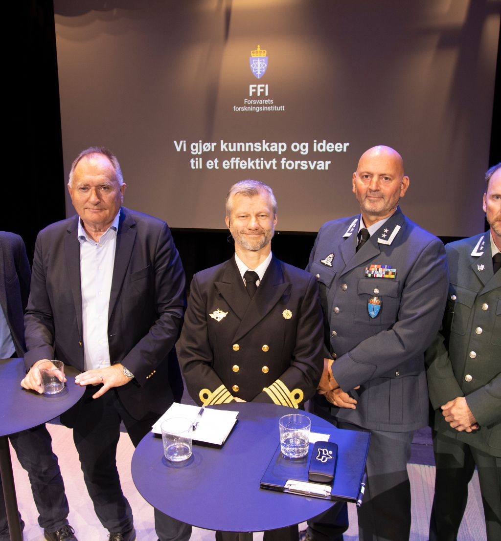 Fem menn står på en scene og ser i kamera