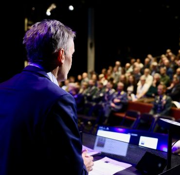 Forskningsdirektør Espen Skjelland på talarstolen framfor ein fullsett Deichmansal i Bjørvika i Oslo.