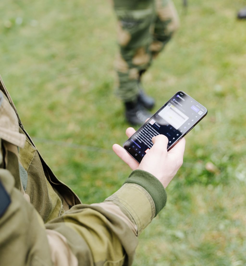 En soldat ser på sosiale medier på mobiltelefonen.