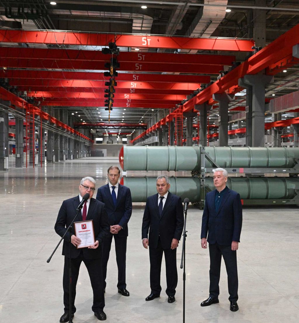 Fire dresskledde menn i en industrihall.
