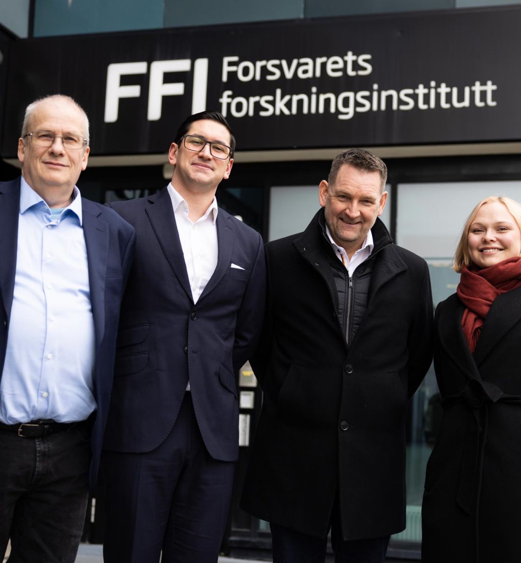 Gruppebilde av Arild Bergh (FFI), Peter Vinje-Banfield, Geir Holmefjord og Silje Lensu Dåbakk (FFI) foran inngangspartiet til FFI. 