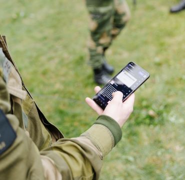 En soldat ser på sosiale medier på mobiltelefonen.