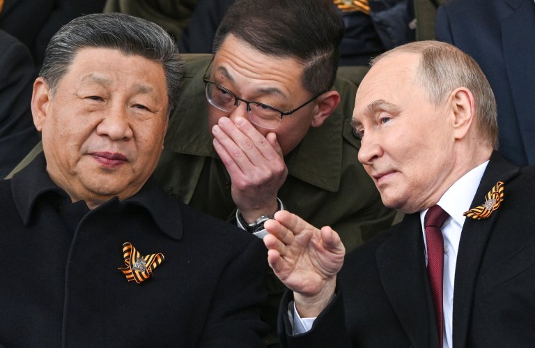 Russian President Vladimir Putin, right, and Chinese President Xi Jinping, left, talk as they watch the Victory Day military parade in Moscow, Russia, Friday, May 9, 2025, during celebrations of the 80th anniversary of the Soviet Union's victory over Nazi Germany during the World War II. (Sergei Bobylev/Photo host agency RIA Novosti via AP)