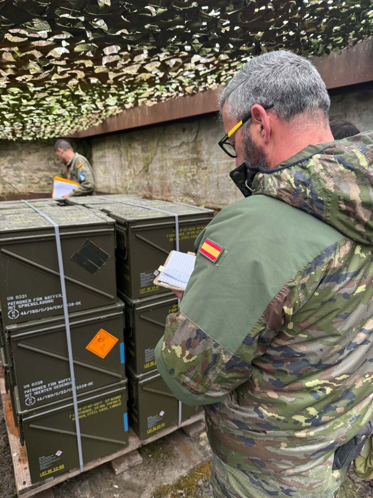 Mann inspiserer ammunisjonslager utendørs.