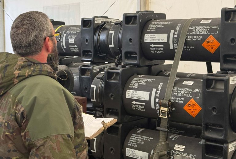 Mann i uniform inspiserer et våpenlager.