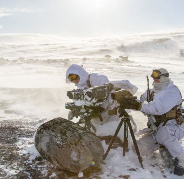To soldater i vinterbekledning monterer utstyr i vinterlandskap